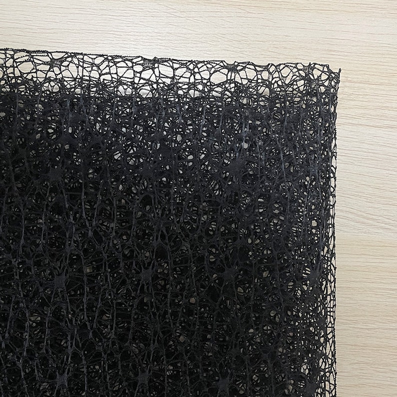 May include: Black netting fabric with a fine, intricate weave. The fabric has a slightly textured surface and a delicate, almost lacy appearance.