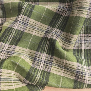 May include: Green and white plaid fabric with a soft, textured feel. The fabric is woven with a subtle sheen and has a slightly irregular weave.