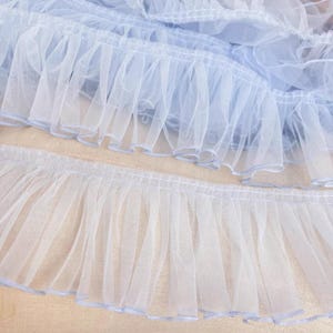 May include: Light blue ruffled trim with a delicate, sheer texture. This trim is perfect for adding a touch of elegance to any project.