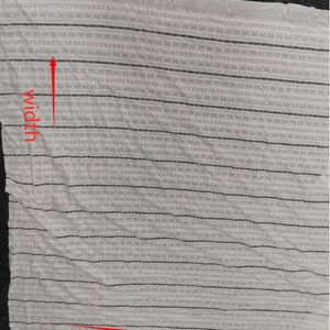 May include: White fabric with black stripes and small white dots. The fabric is folded and the length and width are marked with red arrows. The text "length" and "width" are written in red.