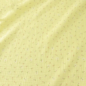 May include: A close-up of a yellow fabric with a floral pattern. The fabric has a textured, ribbed appearance. Tiny white and red flowers are scattered across the surface, creating a delicate, springtime aesthetic.