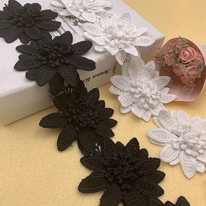 May include: Black and white floral lace trim with a 3D flower design. The trim is made of delicate fabric and is perfect for adding a touch of elegance to any project.