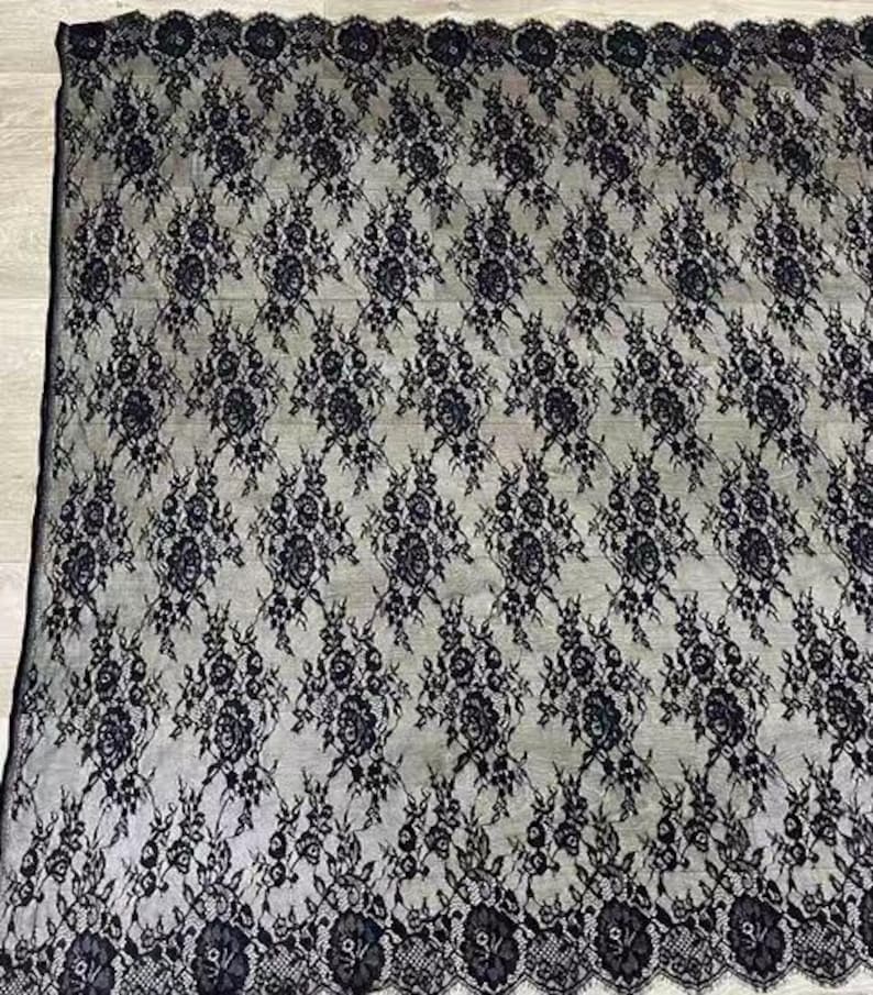May include: Black lace fabric with a floral pattern. The lace has a scalloped edge.