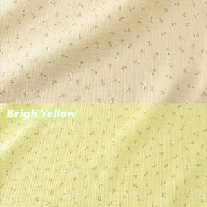 May include: Close-up of two sections of fabric. The top section is apricot-colored and the bottom section is bright yellow. Both fabrics are covered in tiny white and pink floral patterns.