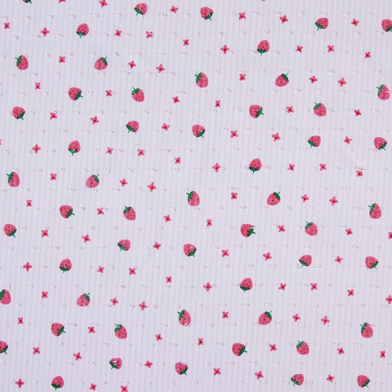 May include: White fabric with a repeating pattern of small pink flowers and red strawberries.