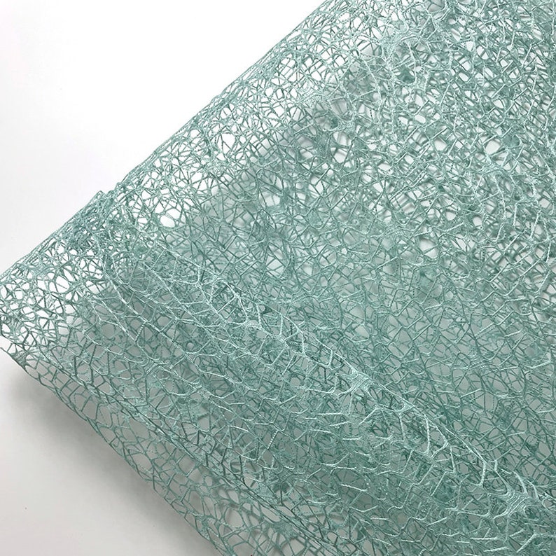 May include: A sheet of light blue, delicate, mesh-like material. The material has a fine, intricate pattern and a slightly shimmery finish.