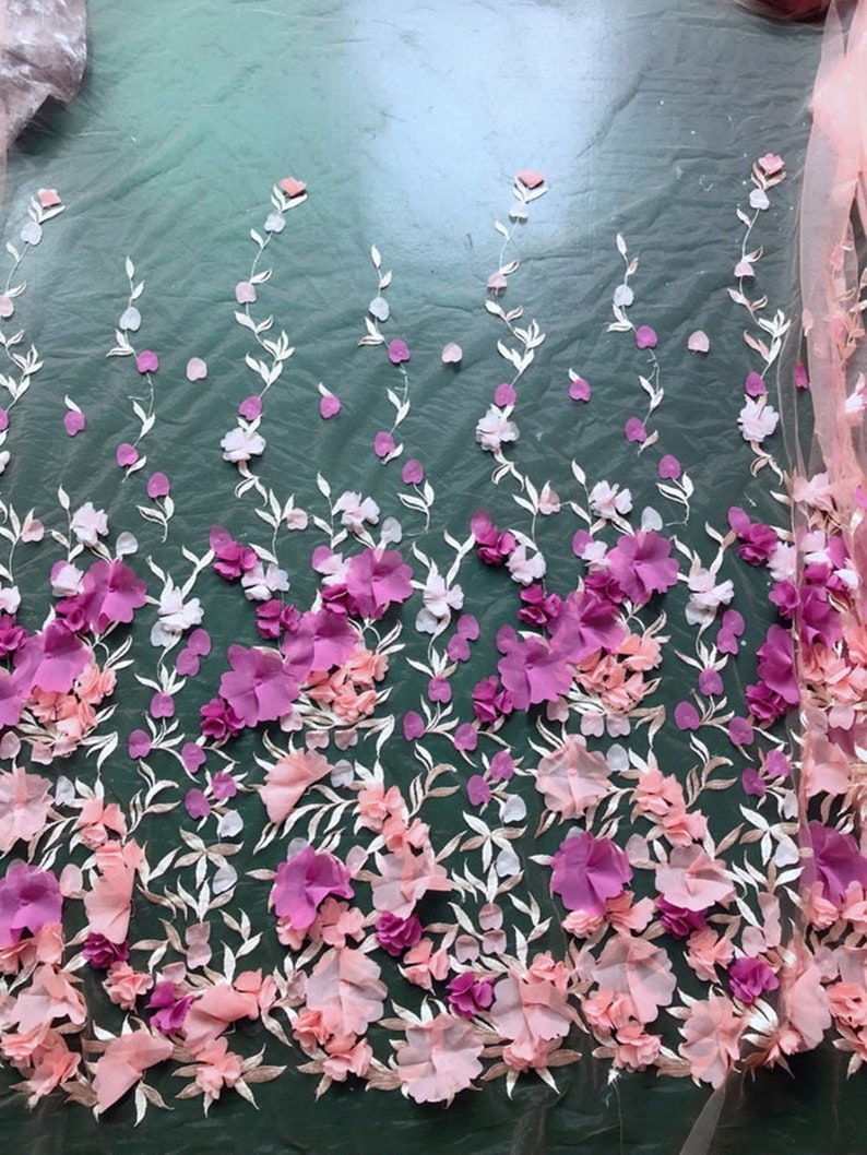 May include: Pink and purple 3D floral lace fabric with a delicate mesh background. The fabric features a repeating pattern of flowers and leaves.