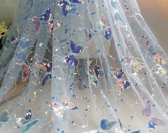 May include: Light blue sheer fabric with iridescent butterfly sequins. The fabric is delicate and has a soft, flowing texture.