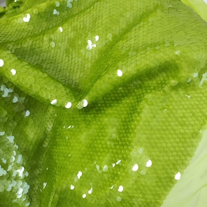 May include: Lime green fabric with sequins. The sequins are small and closely spaced, creating a shimmering effect.