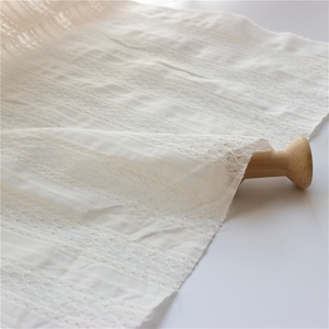 Puede incluir: Tela de algod&oacute;n blanca con un delicado patr&oacute;n de encaje. La tela es suave y transparente, y ser&iacute;a perfecta para una variedad de proyectos de costura.
