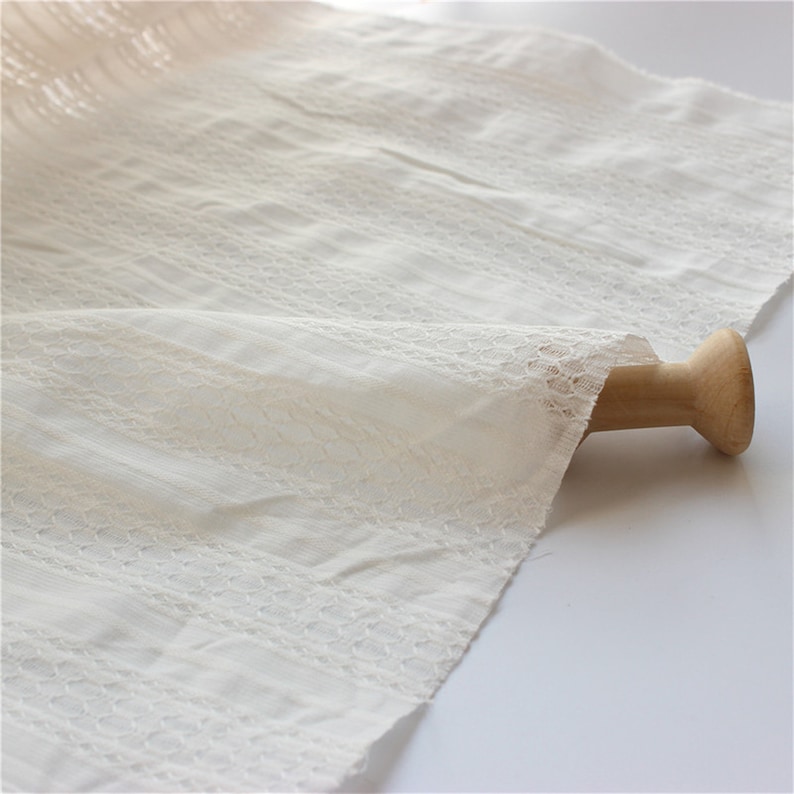 Puede incluir: Tela de algod&oacute;n blanca con un delicado patr&oacute;n de encaje. La tela es suave y transparente, y ser&iacute;a perfecta para una variedad de proyectos de costura.