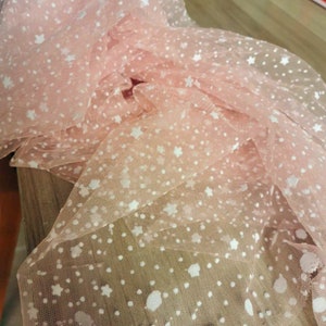 May include: Pink tulle fabric with white star and dot pattern.
