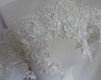 May include: White lace trim with a delicate floral pattern. The lace is soft and flowing, with a scalloped edge.