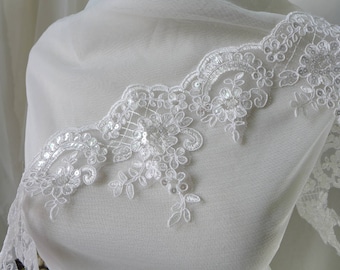May include: Close-up of white lace trim with floral and leaf patterns. The lace is embellished with sequins, adding a subtle sparkle. The delicate design is suitable for bridal wear or other craft projects.