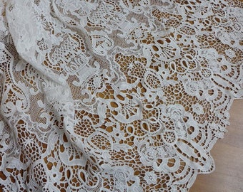May include: White lace fabric with a delicate floral pattern. The lace is intricate and has a soft, flowing texture.