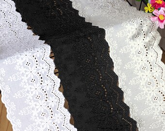 Peut inclure: Trois morceaux de dentelle en coton blanc avec un bord festonné et une broderie florale. La dentelle est disposée en pile, avec la dentelle noire en bas.