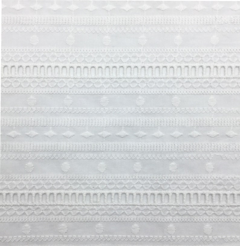 May include: White cotton fabric with an embroidered pattern of circles, diamonds, and scalloped edges.