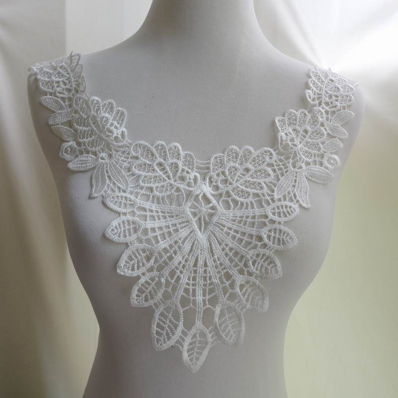 Pu&ograve; includere: Bordino in pizzo bianco con un bordo a festoni e un delicato motivo floreale. Questo bordino &egrave; perfetto per aggiungere un tocco di eleganza a qualsiasi progetto.