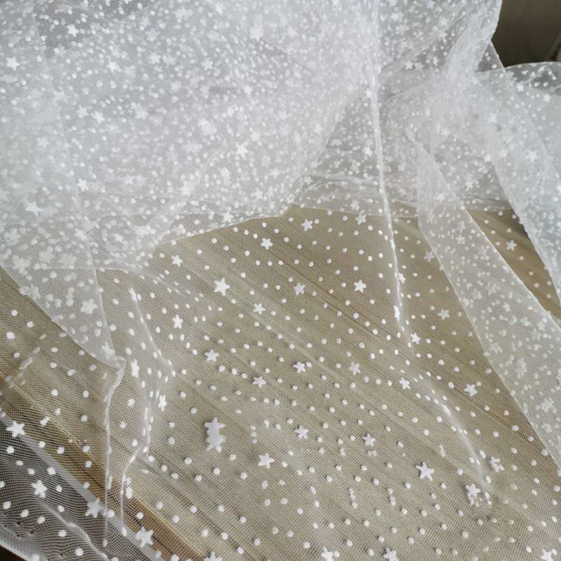 May include: White tulle fabric with a white star and dot pattern.