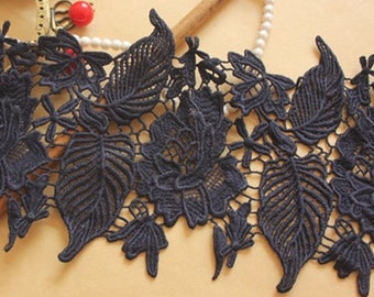 May include: Black lace trim with a floral and leaf design. The lace is delicate and intricate, with a scalloped edge.