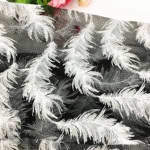 May include: Black sheer fabric with a white feather pattern. The fabric is lightweight and has a delicate texture.