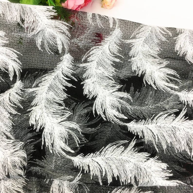 May include: Black sheer fabric with a white feather pattern. The fabric is lightweight and has a delicate texture.