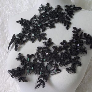 Può includere: Due applicazioni in pizzo nero con paillettes verdi. Le applicazioni hanno la forma di fiori e foglie.