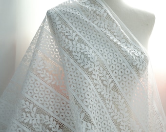 May include: White lace fabric with a delicate floral pattern and small circles. The lace has a soft, flowing texture.