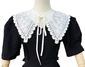 May include: A black dress with a white lace collar. The collar is tied at the neck with a white ribbon.