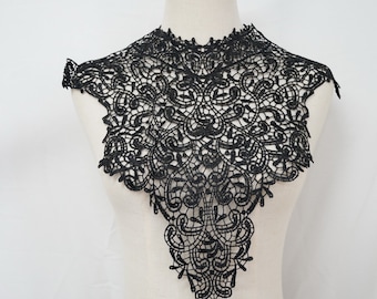 May include: Black lace trim with a delicate floral pattern. The trim is shaped like a collar and has a pointed bottom.