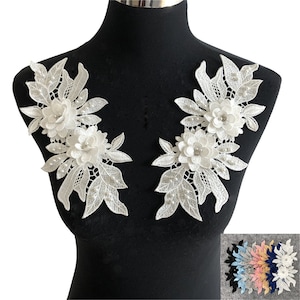 May include: Two white lace appliques with pearl accents and floral designs. The appliques are perfect for adding a touch of elegance to any garment or craft project.