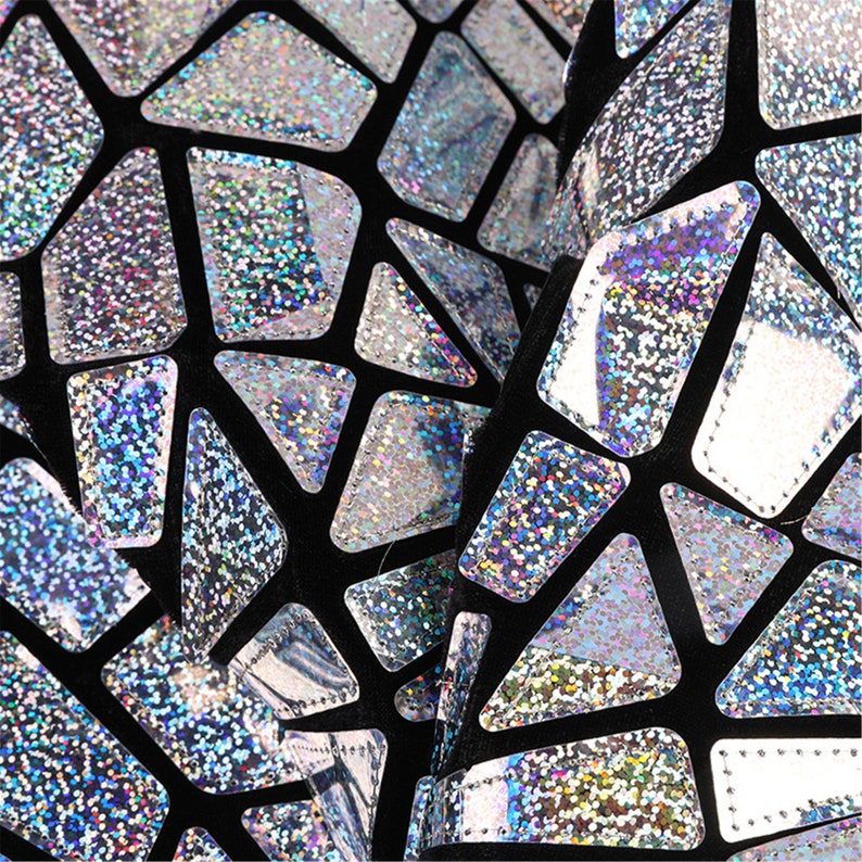 K&ouml;nnte beinhalten: Schwarzer Stoff mit einem geometrischen Muster aus silbernen, glitzernden Formen.