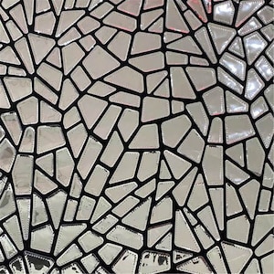 K&ouml;nnte beinhalten: Schwarzer Stoff mit einem silbernen, geometrischen Spiegelmuster. Das Muster besteht aus kleinen, unregelm&auml;&szlig;igen Formen, die zusammengen&auml;ht sind, um einen Mosaik-Effekt zu erzeugen.