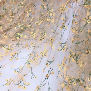 Peut inclure: Un tissu beige transparent avec un motif floral délicat brodé en or et vert.