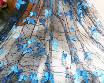 May include: Black mesh fabric with blue butterfly appliques. The fabric is sheer and delicate, with a soft, flowing texture.