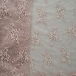 May include: A close-up of two pieces of delicate lace fabric. One piece is a light brown color and the other is a lighter, almost white color. Both pieces feature a floral pattern.