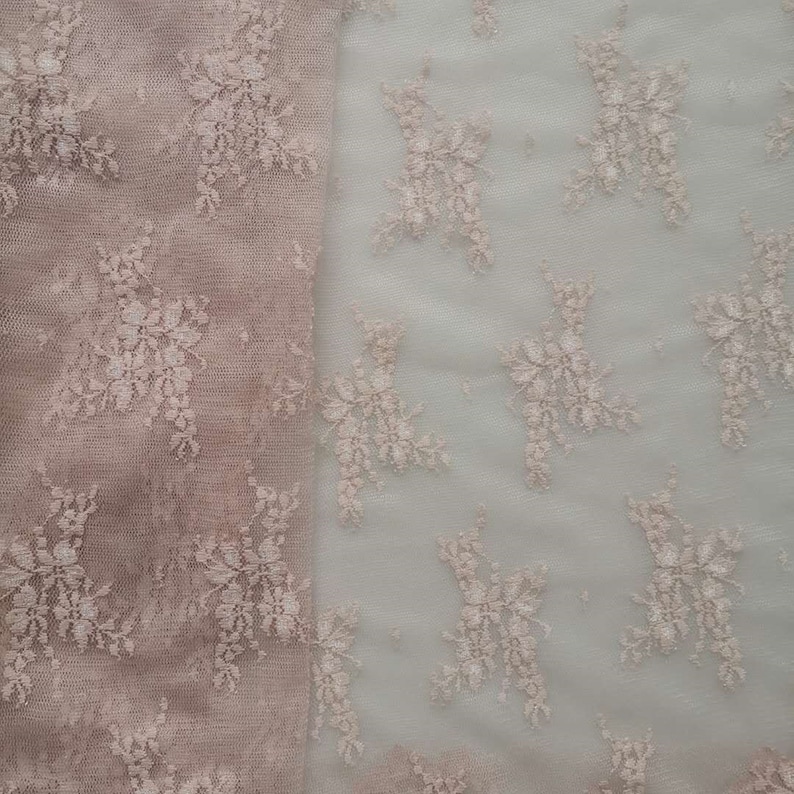 May include: A close-up of two pieces of delicate lace fabric. One piece is a light brown color and the other is a lighter, almost white color. Both pieces feature a floral pattern.