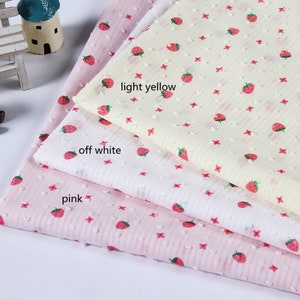 May include: Three pieces of fabric with a strawberry print. The fabric is in three colors: pink, off-white, and light yellow.