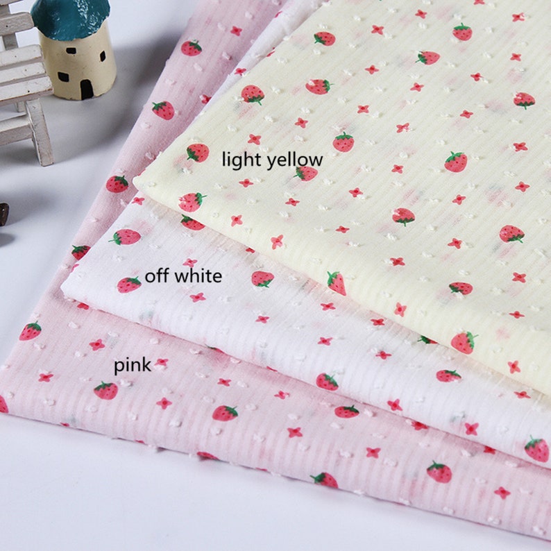 May include: Three pieces of fabric with a strawberry print. The fabric is in three colors: pink, off-white, and light yellow.