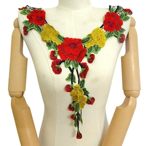 May include: A decorative floral lace applique featuring vibrant red and yellow embroidered flowers with green leaves. The design is arranged in a V-shape neckline pattern with a trailing vine element extending downward, all set against a black mesh base.