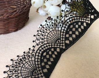 May include: Black lace trim with a delicate floral pattern. The lace has a scalloped edge and is perfect for adding a touch of elegance to any project.