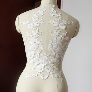 May include: White floral lace applique with delicate embroidery. This lace trim is perfect for adding a touch of elegance to wedding dresses, bridal accessories, and other craft projects.