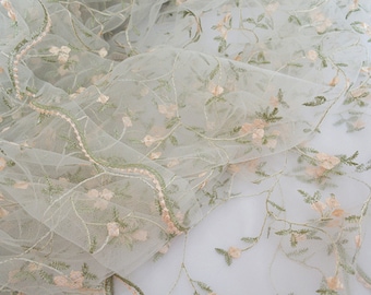 May include: Pale green tulle fabric with delicate embroidered floral vines and small pink flowers.
