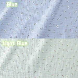 May include: Two sections of fabric, one light blue and one light green, are covered in small white and pink floral patterns. The word "Blue" is written in green text above the light blue fabric, and "Light Blue" is written above the light green fabric.