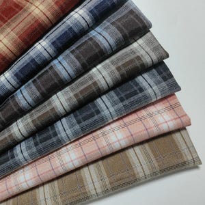 Può includere: Campioni di tessuto a quadri in vari colori, tra cui rosso, blu, marrone e rosa. Il tessuto presenta un classico motivo a scacchi, adatto per progetti di abbigliamento o di arredamento. I campioni sono disposti per mostrare le diverse combinazioni di colori.