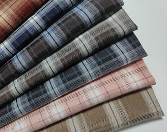 Può includere: Campioni di tessuto a quadri in vari colori, tra cui rosso, blu, marrone e rosa. Il tessuto presenta un classico motivo a scacchi con linee sottili. I campioni sono disposti a ventaglio, mostrando le diverse opzioni di colore.