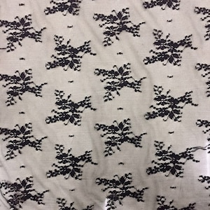 May include: Black lace fabric with a repeating floral pattern.