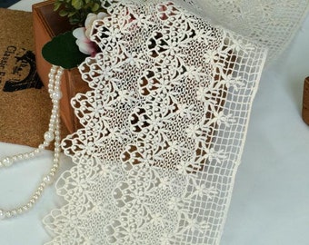 May include: Ivory lace trim with a delicate floral pattern and a mesh backing. The lace has a scalloped edge.