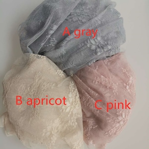 May include: Three pieces of lace fabric in different colors: gray, apricot, and pink. The fabric is delicate and has a floral pattern.