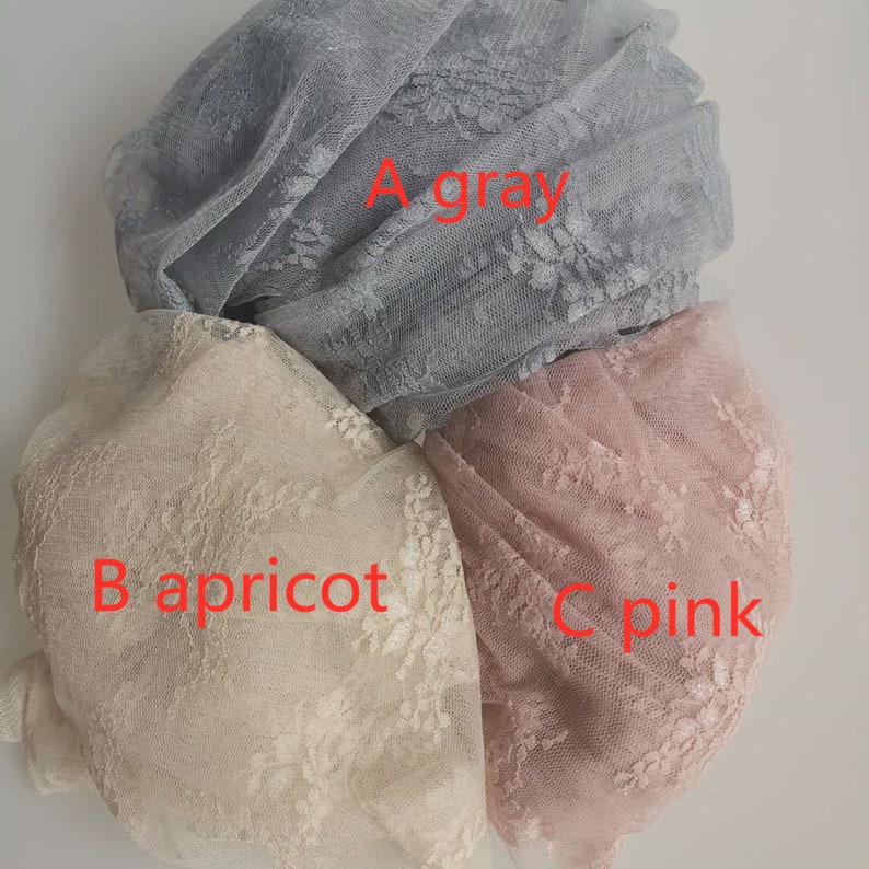 May include: Three pieces of lace fabric in different colors: gray, apricot, and pink. The fabric is delicate and has a floral pattern.